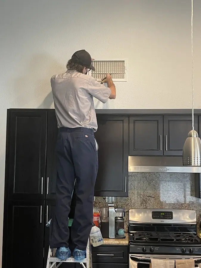 Technician inspecting an air vent during HVAC service in Hempstead